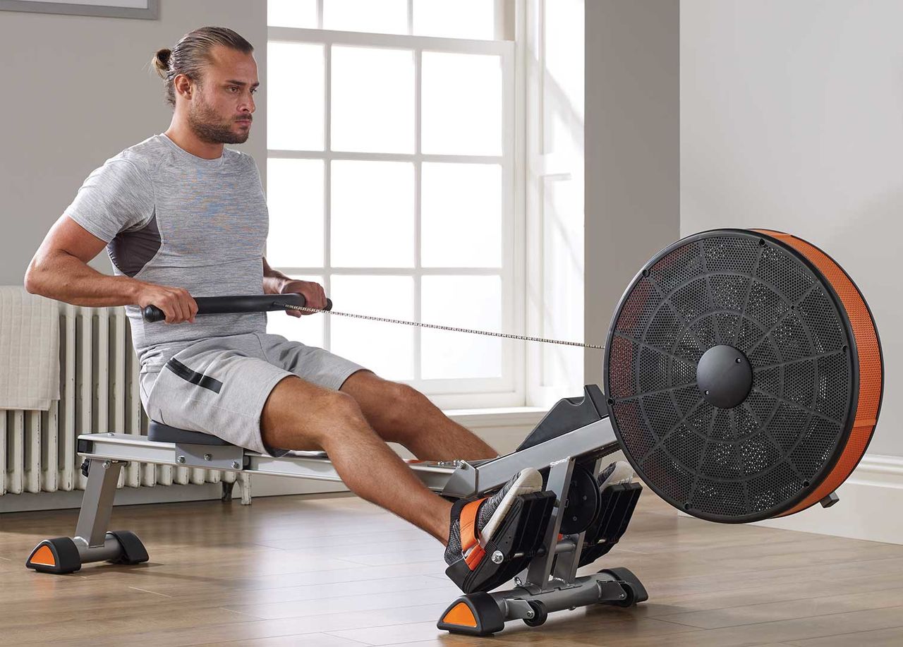 Мужчина тренирует выносливость на гребном тренажере